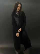 Tapado largo de paño de lana color negro con estampado abstracto brillante en el frente. Tiene cuello con solapas, bolsillos laterales y terminación al tallo vivo.