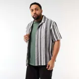 Camisa de manga corta a rayas verticales en tonos negro y blanco, con cuello camisero, cierre frontal de botones y un bolsillo aplicado en el pecho.