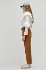 Camisa blanca de popelina de algodón con cuello clásico y botones de nácar. Presenta volados dobles decorativos que recorren el frente y la espalda desde el hombro hasta la cintura, además de volados en las mangas a la altura del codo.