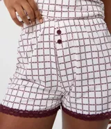 Short de pijama femenino confeccionado en tejido peach touch de poliéster, con cintura elastizada, botones frontales y encaje bordó en los bajos. Presenta un estampado geométrico con pequeños corazones en tonos blancos y oscuros.