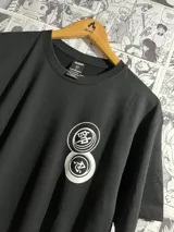 Remera negra de algodón con estampado frontal de dos círculos blancos con caracteres japoneses.