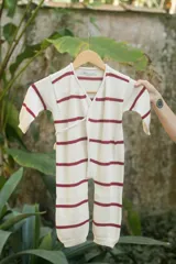 Enterito tejido a rayas horizontales color crudo y rojo, con mangas largas y cierre cruzado con lazo lateral.