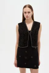 Chaleco negro de algodón sin mangas, con escote en V y bordados detallados.