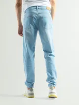 Jean negro de corte slim fit, tiro medio, con cierre y botón. Presenta un ligero desgaste en la zona de los muslos.