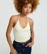 Blusa cropped color crema de frente única con escote en V y tirantes finos para anudar al cuello, confeccionada en algodón con elastano.