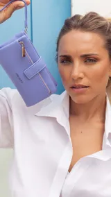 Billetera de mano marca Lincoln's, color lila, con textura granulada, cierre de broche a presión y compartimento externo con cierre metálico. Incluye correa de muñeca extraíble.