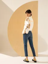 Jeans slim de tiro medio color azul, con largo al tobillo y parches bordados de labios rojos en el bolsillo delantero.