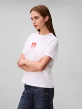 Remera Calvin Klein de algodón color blanco, con cuello redondo, mangas cortas y estampa frontal cuadrada con el monograma cK en tonos degradados de rojo y rosado.