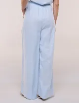 Conjunto de dos piezas confeccionado en lino, de estilo casual safari. Incluye camisa de manga corta con cuello camisero con bordado festoneado, abotonadura frontal y bolsillos en el pecho; y pantalón palazzo de tiro alto con bolsillos y cinturón con hebilla metálica dorada.