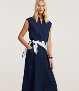 Vestido tipo chemise sin mangas, de corte midi y botonadura frontal completa. Confeccionado en una mezcla de lino y viscosa, presenta un diseño liso con bolsillos laterales y un pañuelo estampado a rayas utilizado como cinturón para ajustar la cintura.