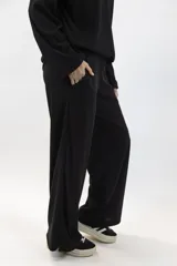 Pantalón negro de tejido acanalado, de corte amplio y tiro alto, con bolsillos laterales.