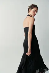 Vestido largo negro de cuello halter, espalda descubierta y escote redondo. Presenta un diseño de punto combinado en la parte superior y una falda larga de tejido fluido.