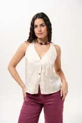 Chaleco de escote en V con silueta entallada y cierre frontal de botones, confeccionado en tela tipo nylon amasado de color manteca con textura y sutil brillo.