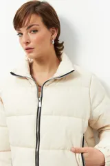 Campera puffer corta color crema de nylon, con cuello alto, cierre frontal con cremallera, bolsillos laterales con cierre y cordones ajustables en la cintura.