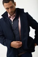 Gabán azul marino con cuello alto y pechera desmontable con cierre.