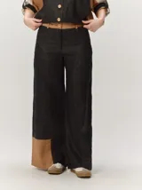 Pantalón sastrero de corte ancho, color beige con rayas verticales blancas y detalles de costuras pespunteadas.