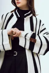 Cardigan de punto a rayas verticales blancas y negras, con mangas largas amplias y diseño abierto al frente.