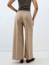 Pantalón de vestir color beige con finas rayas verticales, corte palazzo y tiro alto.