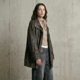 Chaqueta de cuero con acabado texturizado, corte recto y largo medio. Presenta cuello camisero, cierre frontal con cremallera y solapa con botones a presión, bolsillos laterales con solapa y puños ajustables con trabillas.