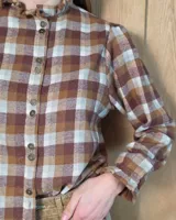 Camisa de algodón con estampado de rayas verticales finas, cuello alto con volados, cierre frontal con botones dobles y mangas largas con puños elásticos terminados en volados.