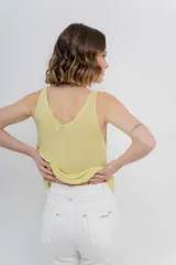 Musculosa tejida color amarillo pálido, con escote en V delantero y trasero.