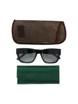 Lentes de sol unisex RKF modelo Genova, con montura cuadrada negra y lentes grises. Incluye estuche rígido marrón y paño de limpieza verde con logo RKF.