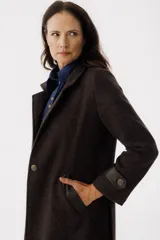 Tapado largo color marrón con solapas, cierre con botones y bolsillos laterales.