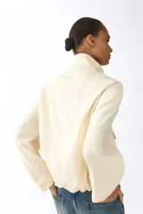 Campera corta de sarga con cuello elevado, solapa rompevientos con cierre y botones a presión ocultos. Diseño oversized con hombros caídos, bolsillos delanteros de fuelle con solapa y cordón elástico ajustable en el bajo.