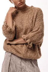 Sweater de tejido de punto con silueta relajada, cuello redondo y mangas 3/4 abullonadas con puños ajustados que aportan volumen.