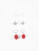 Set de tres pares de caravanas plateadas: un par de aros tipo botón con forma de media luna, un par de aros tipo botón con forma de flor con incrustaciones verdes y un par de aros colgantes con forma de racimo de uvas rojas.