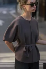 Jersey de punto color marrón, con cuello redondo, mangas cortas abullonadas y detalle de lazo frontal en la cintura.