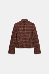 Blazer de cuello subido y manga larga, con diseño peplum en el bajo y cierre frontal con botones. Confeccionado en tejido texturizado a cuadros.
