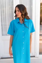 Vestido camisero de muselina color negro, de largo midi, con cuello clásico, manga corta y cierre frontal con botones.