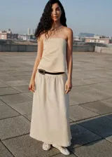 Top strapless color beige, con escote palabra de honor, diseño entallado, fruncido lateral y bajo deshilachado. Cuenta con cierre de cremallera lateral.