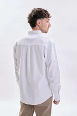 Camisa de manga larga oxford en color blanco, con cuello abotonado y bolsillo frontal en el pecho.