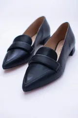 Mocasines negros de cuero con punta fina y detalle de antifaz.