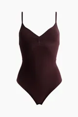 Body tanga modelador color bordó, con efecto vientre plano y sin aros. Presenta escote en V, copas forradas con fruncido central que realza el busto y tirantes finos regulables. Diseño sin costuras laterales para mayor comodidad.