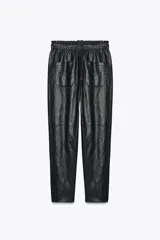 Pantalón tobillero de tiro medio color marrón oscuro, con cintura elástica ajustable con cordón y herretes dorados. Incluye bolsillos delanteros y bolsillos de plastrón en la espalda.