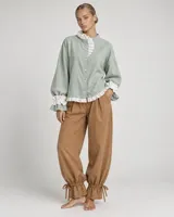 Pantalón azul deslizante de corte ancho, con cintura elástica y puños fruncidos ajustables mediante tiras atadas en los tobillos.