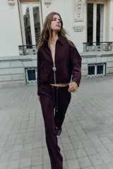 Cazadora bomber de Zara, de color bordó, con cuello de solapa, manga larga, bolsillos de vivo en el delantero y bajo elástico. Cuenta con cierre frontal de cremallera metálica.
