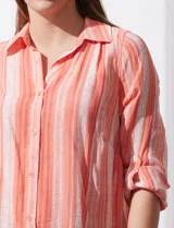 Camisa larga de rayón, con cuello clásico, cierre frontal con botones y mangas regulables con presilla. Presenta un diseño holgado con tajos laterales en el ruedo.