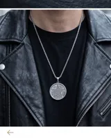 Collar de acero con dije circular grabado con el símbolo del Tetragramaton y cadena de eslabones finos.