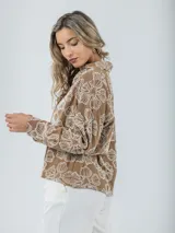 Blusa marrón rústica con bordado de flores blancas, cuello camisero y mangas largas.