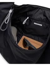 Bolso tipo hobo de diseño ergonómico y minimalista en color negro, con tecnología resistente al agua. Presenta una estructura curva, correas ajustables con detalles de cordones técnicos y cierre principal con tiradores multifuncionales.