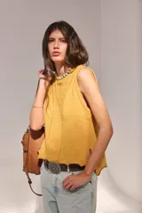 Chaleco de punto de lambswool color mostaza, sin mangas, con cuello redondo y diseño de ochos en la parte delantera.