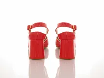 Sandalias de cuero charol color coral con taco mediano forrado, diseño open toe y tira ajustable en el talón. Presenta un aplique decorativo desmontable en forma de corazón blanco en la parte delantera.