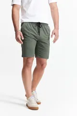 Bermuda de gabardina color verde militar, con cintura elástica y cordón de ajuste. Cuenta con diseño de cinco bolsillos y corte recto.