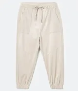 Pantalón jogger Marfinno color beige, confeccionado en suedine con cintura elástica y cordón ajustable. Presenta detalles perforados en los bolsillos laterales y en las costuras laterales, además de puños elásticos en los tobillos.