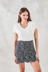 Minifalda negra con bordado blanco de motivos geométricos y terminación festoneada.