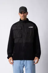 Campera de estilo urbano confeccionada en una combinación de micro polar y paneles de tela técnica tipo sire. Presenta cierre frontal completo, cuello alto y bolsillos funcionales en el pecho. Incluye un parche con logo en el frente y diseño estampado en la espalda.